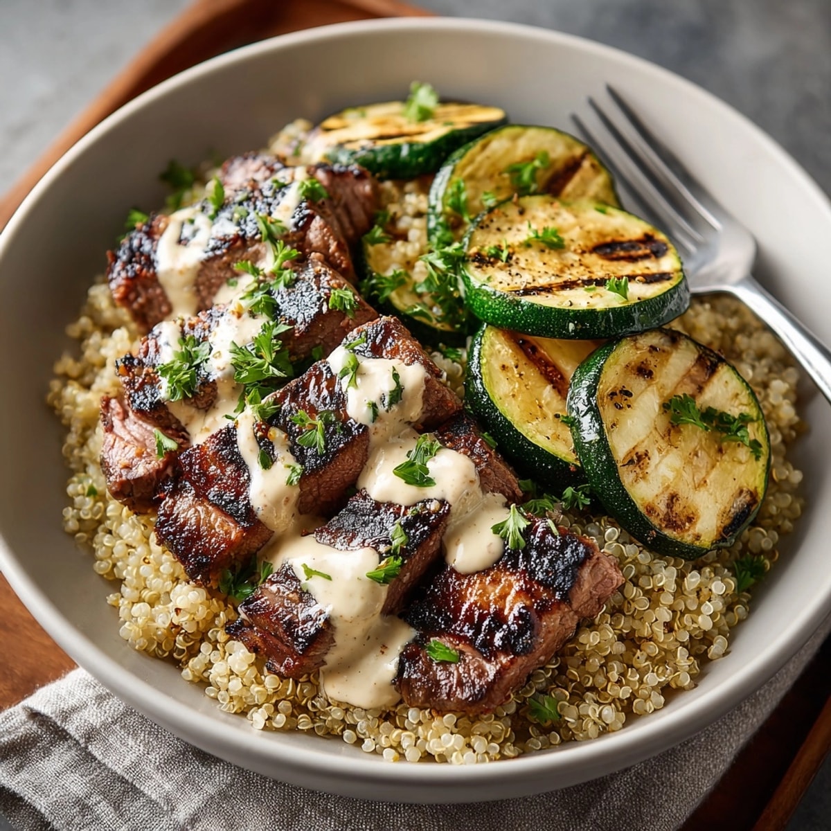 Grilled Steak Bowl with Creamy Sauce & Grilled Zucchini topped with herb drizzle on quinoa