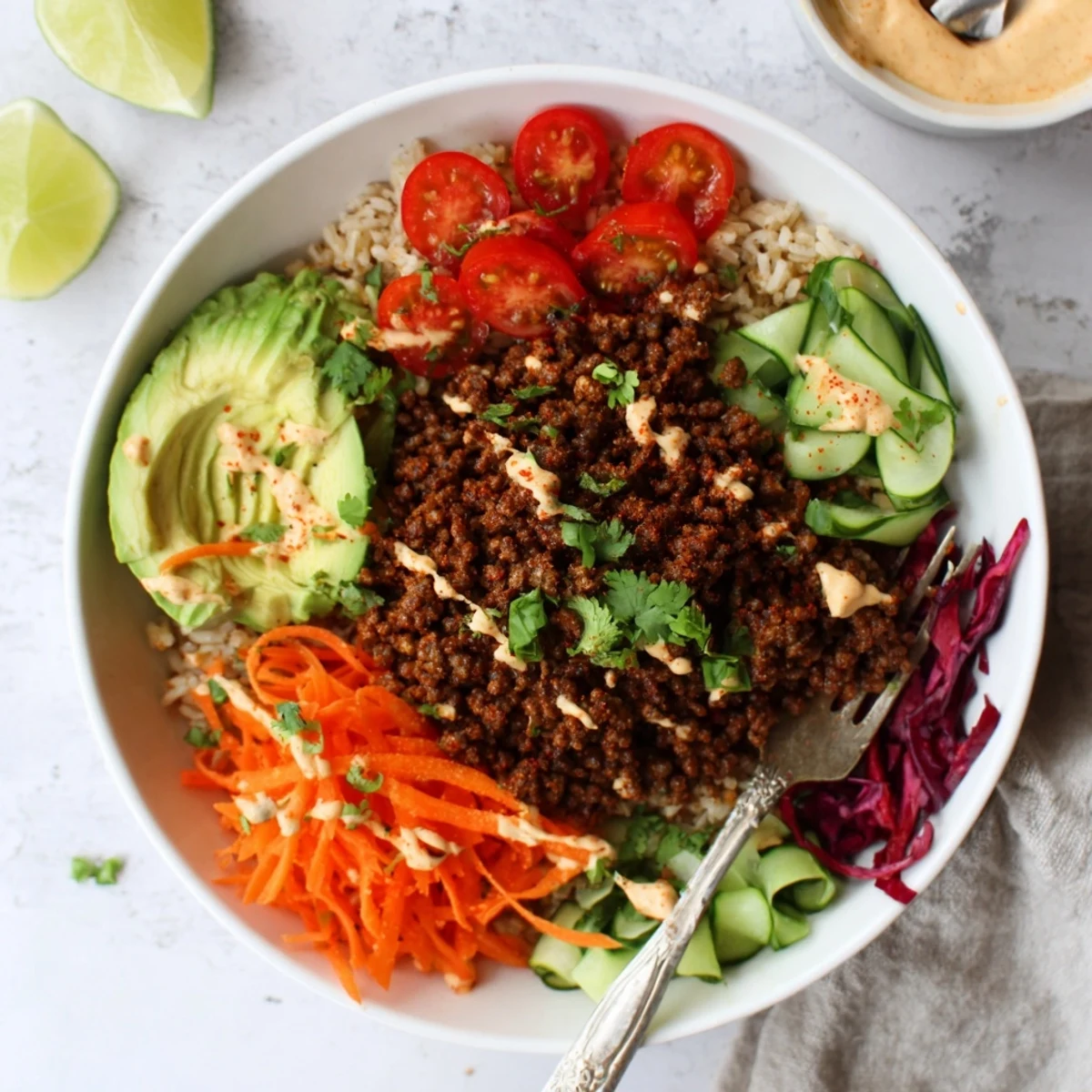 A colorful Plant-Based Meat Bowl featuring fresh veggies and zesty lime wedges.  