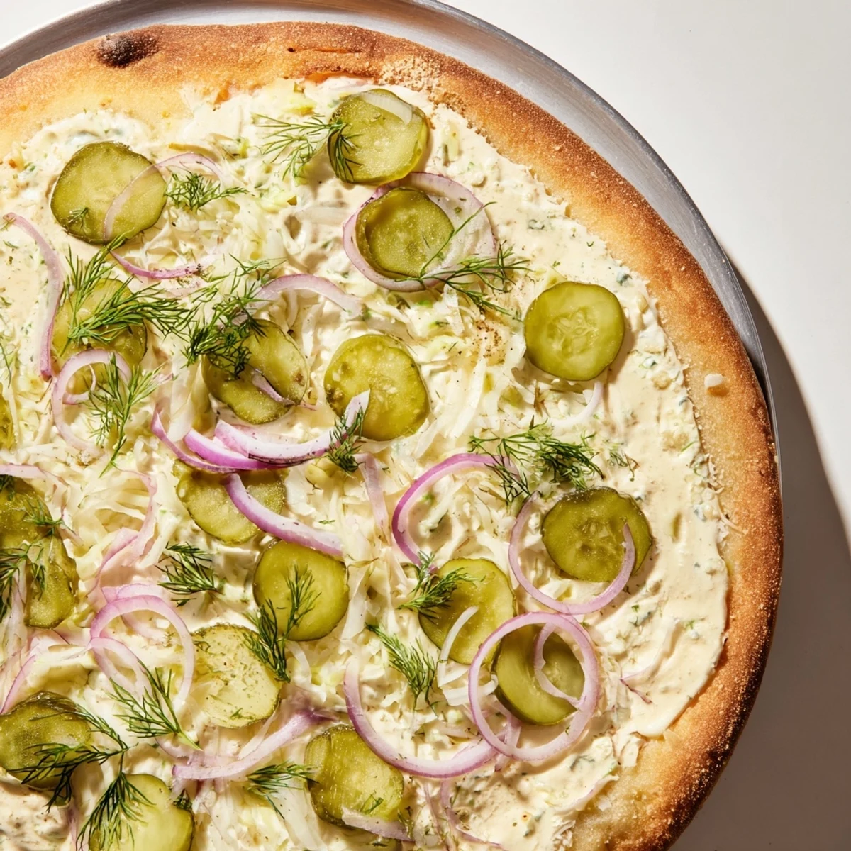 Tangy pickle pizza with creamy sauce, vibrant mozzarella, and crunchy dill toppings.  