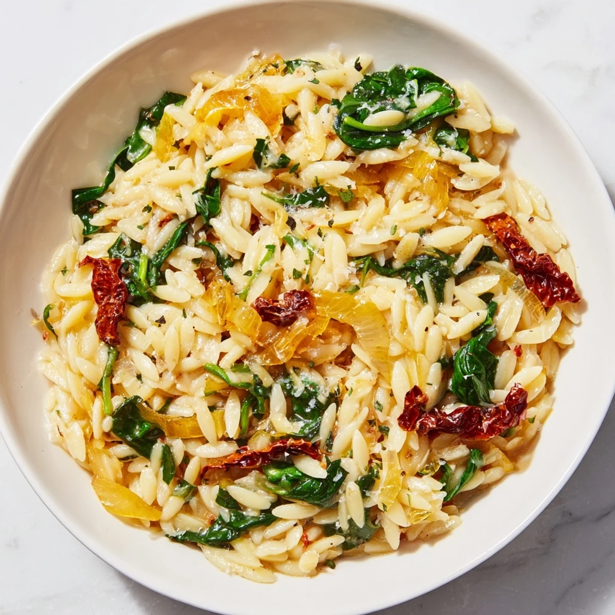 Creamy Tuscan Orzo Bowl with spinach and sun-dried tomatoes, ready to be served hot.