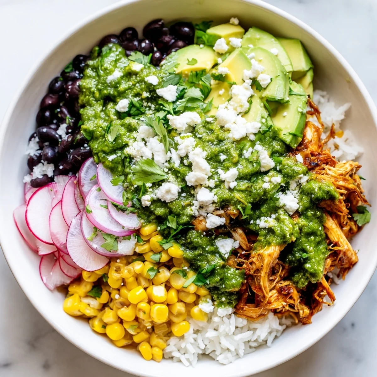 A colorful Green Enchiladas Rice Bowl overflowing with chicken, fresh cilantro, and creamy avocado slices.