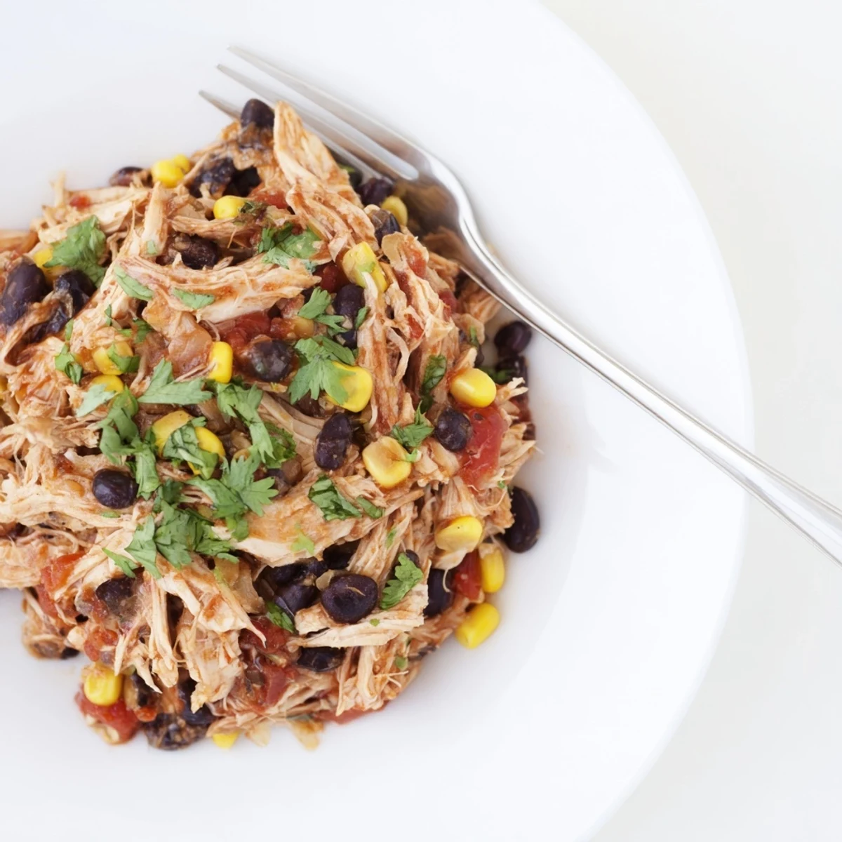 Juicy, shredded Slow Cooker Salsa Chicken, perfect for tacos, boasting vibrant red salsa sauce.