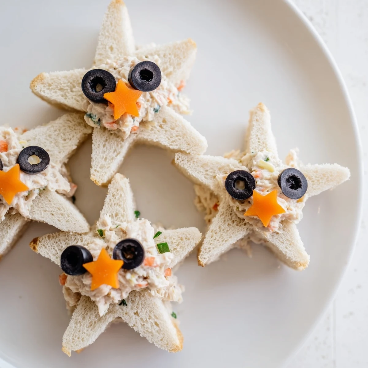Freshly assembled mini starfish sandwiches, showing a festive tuna salad creation for a delightful appetizer platter.