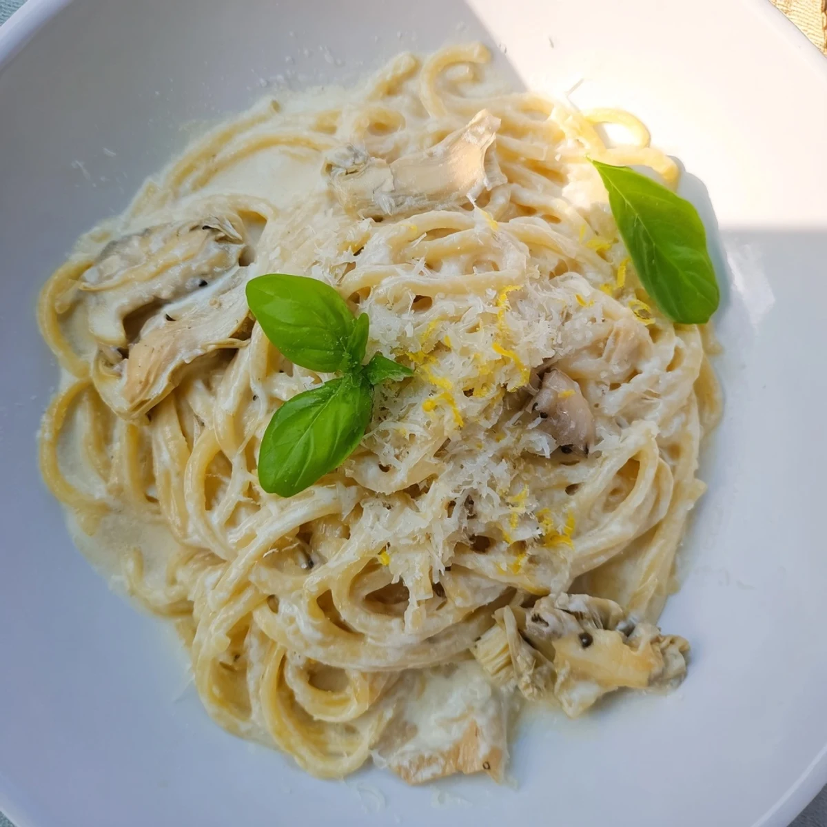 Steaming plate of Creamy Lemon Artichoke Pasta, garnished with basil, ready for a delicious meal.