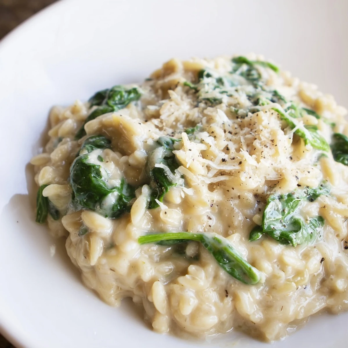 Creamy spinach orzo, a one-pan meal, bubbling gently in a skillet, ready to serve with Parmesan.