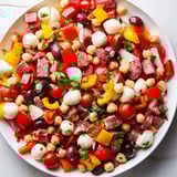 A colorful bowl of Crunchy Antipasto Chopped Salad served as a light lunch, garnished with fresh basil and parsley.