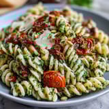 Colorful pasta salad featuring homemade pesto, juicy cherry tomatoes, and parmesan shavings, ideal for picnics or light lunches.
