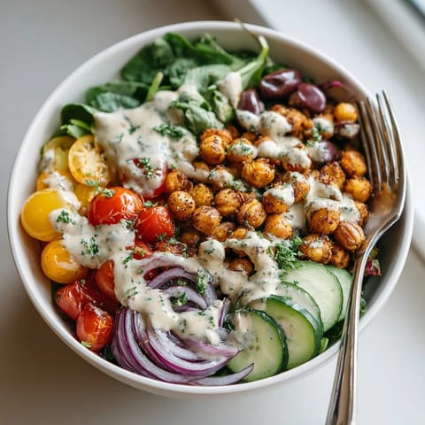A healthy Mediterranean Chickpea Power Bowl, bursting with fresh veggies and creamy tahini dressing drizzled over.