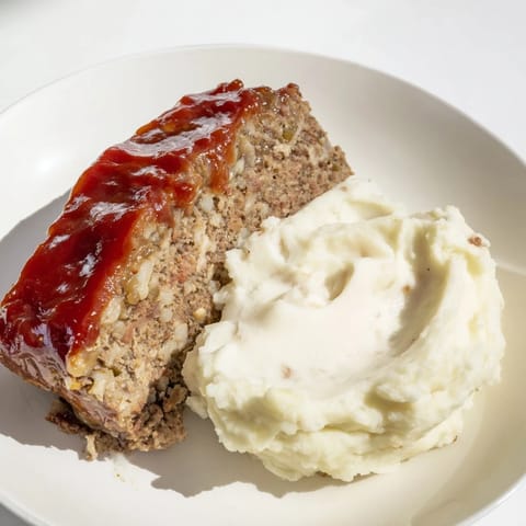 A plate of Classic Meatloaf & Mashed Potatoes, a hearty meal perfect for a family dinner.