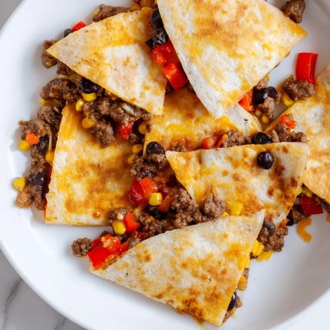 Golden and crispy Sheet Pan Quesadillas with Beef are shown, ready to be sliced and served with toppings.