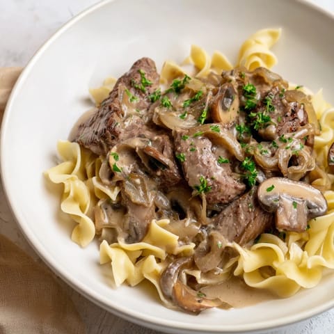 Sizzling beef stroganoff with golden mushrooms and silky sauce, perfect served with warm egg noodles.
