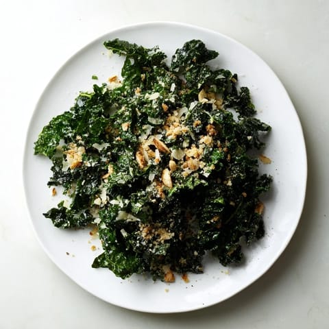 A close-up of the Garlic Parmesan Kale Salad with shaved Parmesan, glistening dressing, and crisp panko, perfect for a light lunch.  
