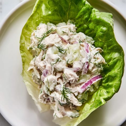 Freshly prepared Dill Pickle Chicken Salad Lettuce Cups arranged on a white platter, featuring tender chicken chunks, diced red onion, and a sprinkle of fresh dill for a zesty, low-carb meal.