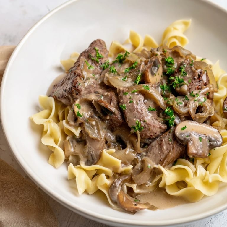 Sizzling beef stroganoff with golden mushrooms and silky sauce, perfect served with warm egg noodles.