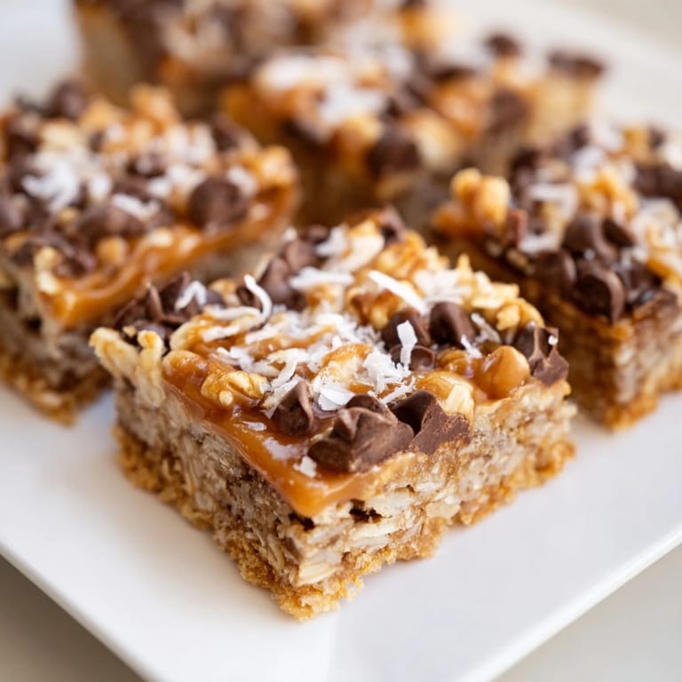 A close-up of delicious 7-Layer Magic Bars showing the perfect mix with a caramel drizzle and nuts.