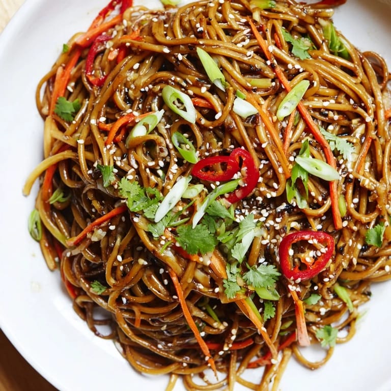 Flavorful Asian Garlic Noodle Bowl topped with chili and carrots, perfect for a delicious vegetarian dinner.