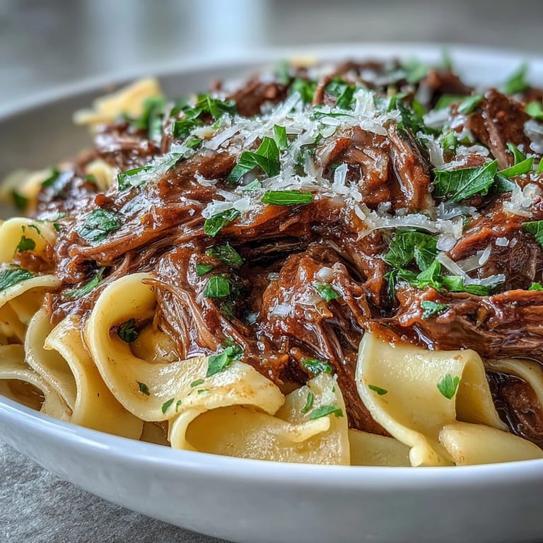 Plate of Crockpot French Onion Pot Roast Pasta with rich onion gravy, ready to serve with crusty bread.